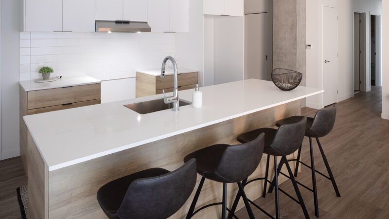 Loges600_Cuisine2-075-C_low Cuisine avec îlot en quartz blanc et tabourets, Loges 600 – LOGES Saint-Nicolas, Lévis